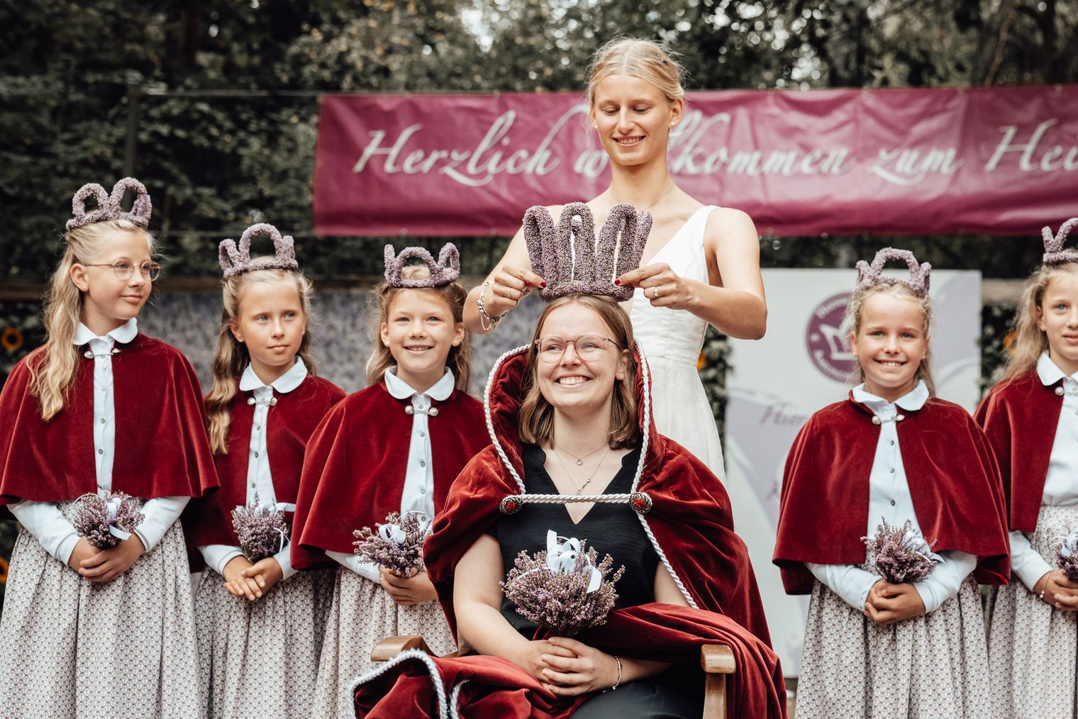 Die alte Heidekönigin Amelinghausen krönt die neue Heidekönigin mit einer Heidekrone. Hinter den beiden steht der sogenannte Hofstaat.