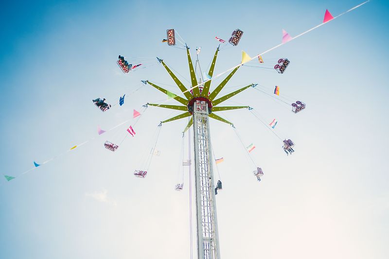 Kettenkarussell auf dem Frühjahrsmarkt vor hellem Himmel, Teilnehmer fliegen in der Luft im Kreis 