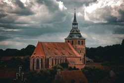 Große Backsteinkirche St. Michaelis in Lüneburg mit markantem Turm unter einem Wolkenhimmel.